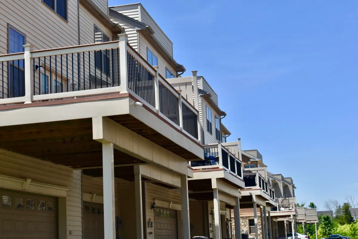 Row of modern townhouses with balconies and garages, set against a clear blue sky.